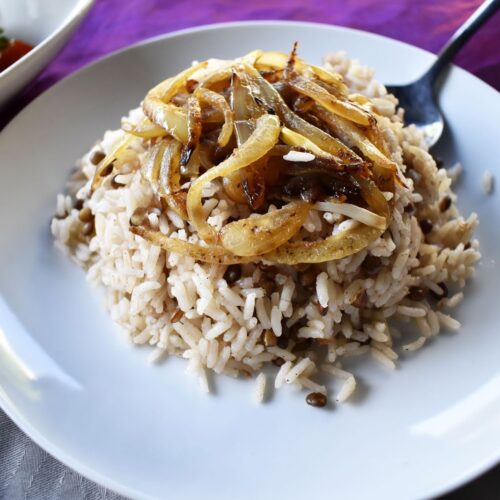 Lentils and Rice (Mujaddara) served on a white plate, topped with golden caramelized onions and ready to enjoy.