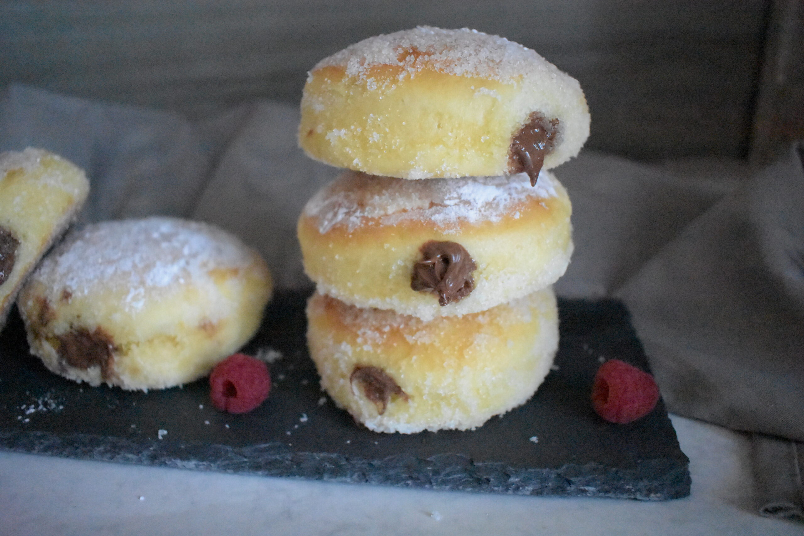 Baked Donuts Filled with Nutella served in a black plate and covered with powder sugar