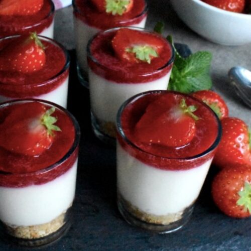 6 shots of strawberry cheesecake, topped with strawberry sauce and fresh strawberry served on a square black stone plate