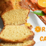 Moist pound orange cake glazed with orange sauce and served on a white plate, garnished with fresh orange slices on the side