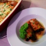 Cheesy meat-stuffed eggplant rollatini casserole baked in tomato sauce and topped with golden melted mozzarella and parmesan, served hot in a rustic oven dish.