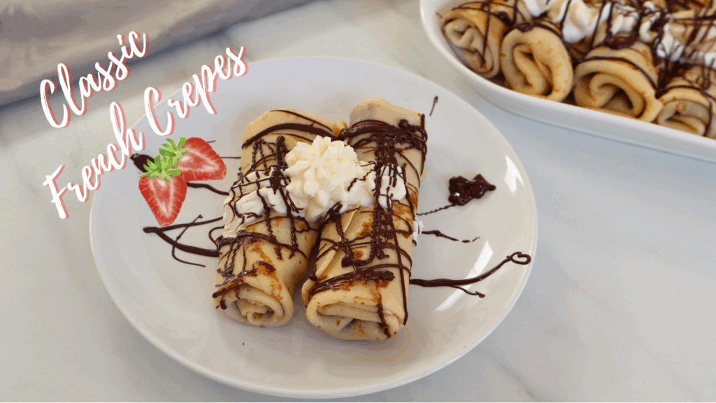Classic French crepes served on a white plate, topped with whipped cream and drizzled with melted chocolate.