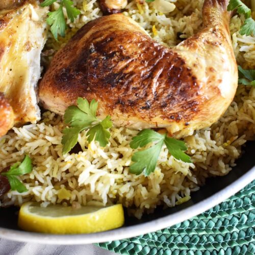 Authentic Middle Eastern Rice and Chicken Kabsa served in a traditional pot, garnished with fresh parsley and lemon slices.