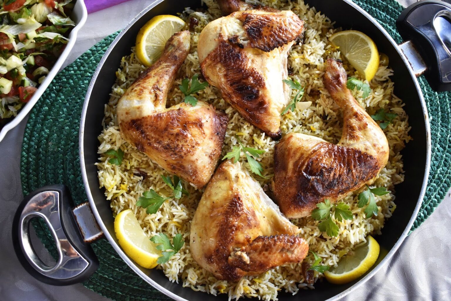 Authentic Middle Eastern Rice and Chicken Kabsa served in a traditional pot, garnished with fresh parsley and lemon slices.